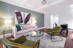 A modern living room with a sofa, two armchairs, a coffee table, and a dining area with a table and chairs.