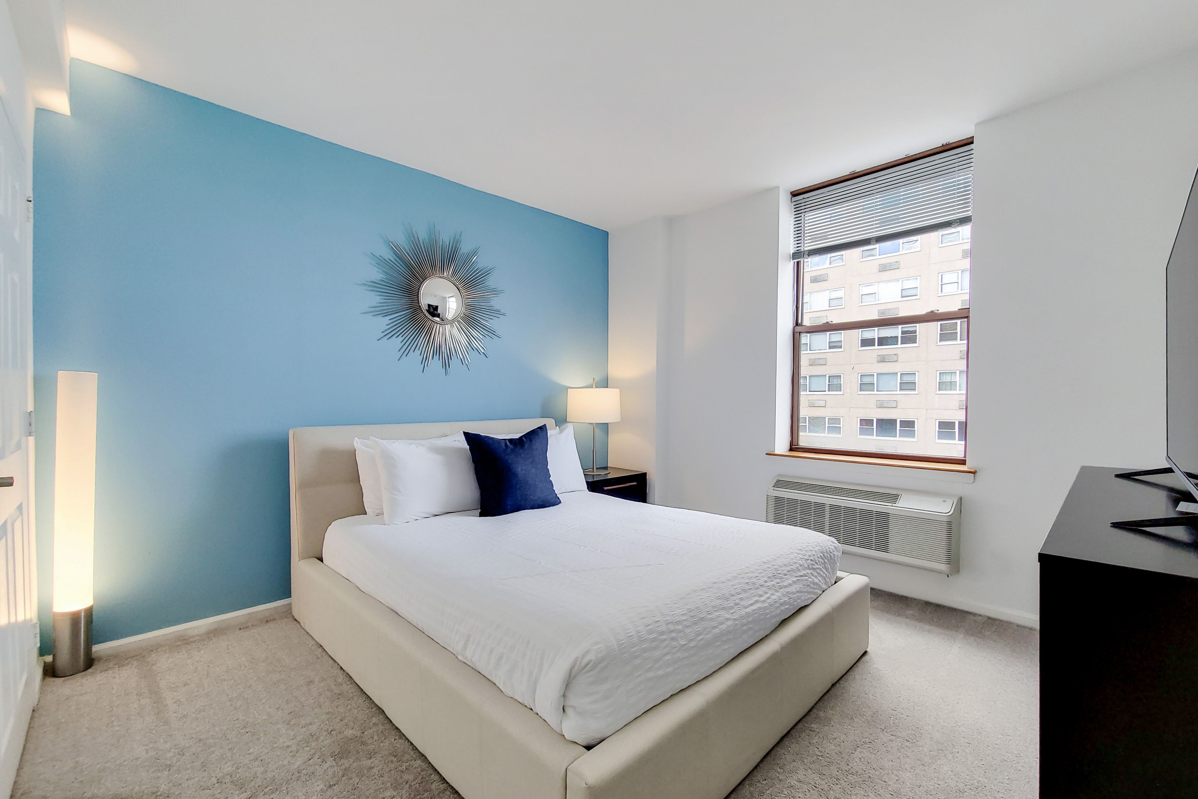 Un dormitorio con cama, un reloj de pared, una ventana y un radiador.