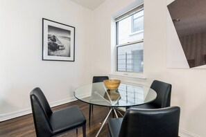 A modern dining area with a glass table, black chairs, and a framed picture on the wall.