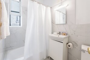 A modern bathroom with a white bathtub, a white sink, and a toilet.