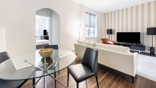 Un salon moderne avec une table à manger en verre, un canapé en cuir et un téléviseur à écran plat.