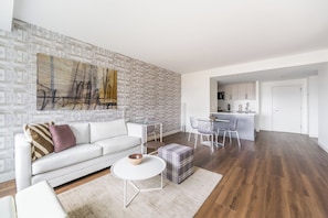 A modern living room with a white sofa, a coffee table, and a dining area with a small table and chairs.