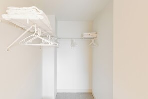 Ein weißer Kleiderschrank mit mehreren Regalen und Platz zum Aufhängen, der ordentlich gefaltete Handtücher und Kleidung beherbergt.