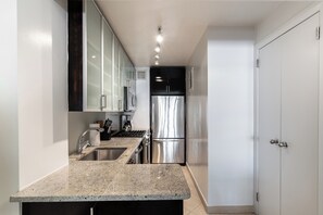 A modern kitchen with granite countertops, stainless steel appliances, and white cabinetry. - Elegant Murray Hill | Fitness Center & Laundry (New York)