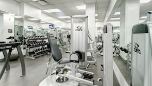 Ett gym med olika typer av träningsutrustning, inklusive hantlar, en bänkpress och en träningsmaskin från Cybex.