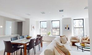 Una sala de estar moderna con comedor, ventanas amplias y vista a la ciudad.