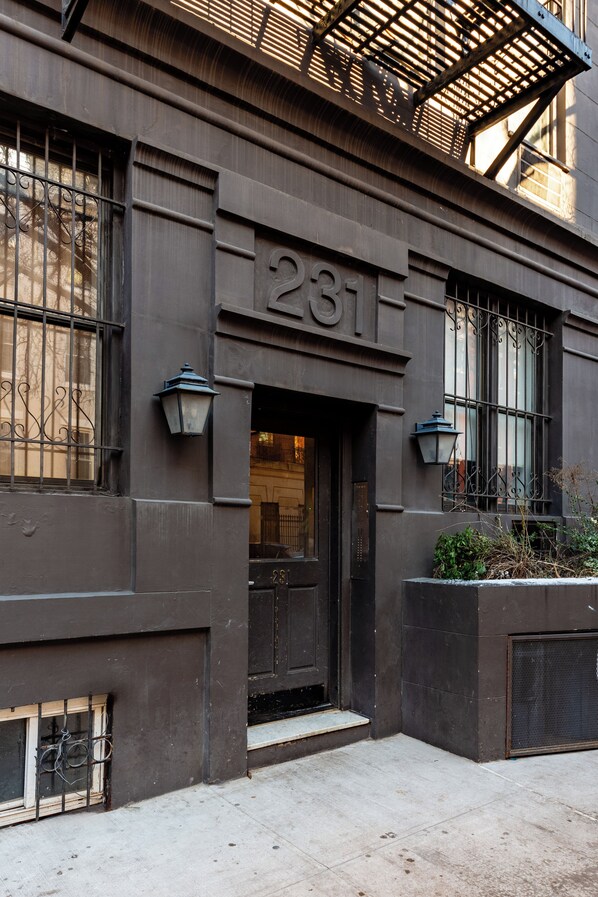 A building facade with a dark-colored entrance, a visible door number '281', and a small window with a metal grille.