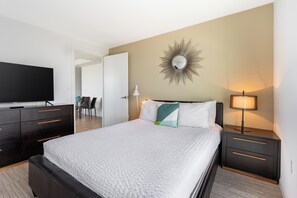 Una habitación de hotel con cama, televisión, escritorio y silla.
