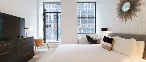 Une chambre d’hôtel moderne équipée d’un grand lit, d’une télévision, d’un bureau et d’une chaise.