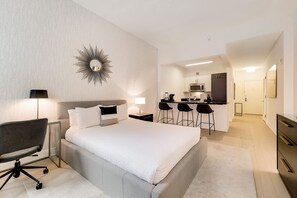 Une chambre d’hôtel moderne équipée d’un grand lit, d’un bureau, d’une chaise, d’une kitchenette et d’une salle de bain.