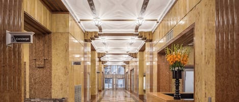 Ein Hotelgang mit einer Rezeption, Mülleimern und einem Check-in-Schalter.