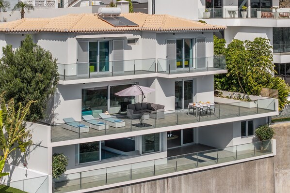 A modern multi-story house with a rooftop terrace, large windows, and a swimming pool. - Villa Harmonia by Homie (Ponta do Sol)