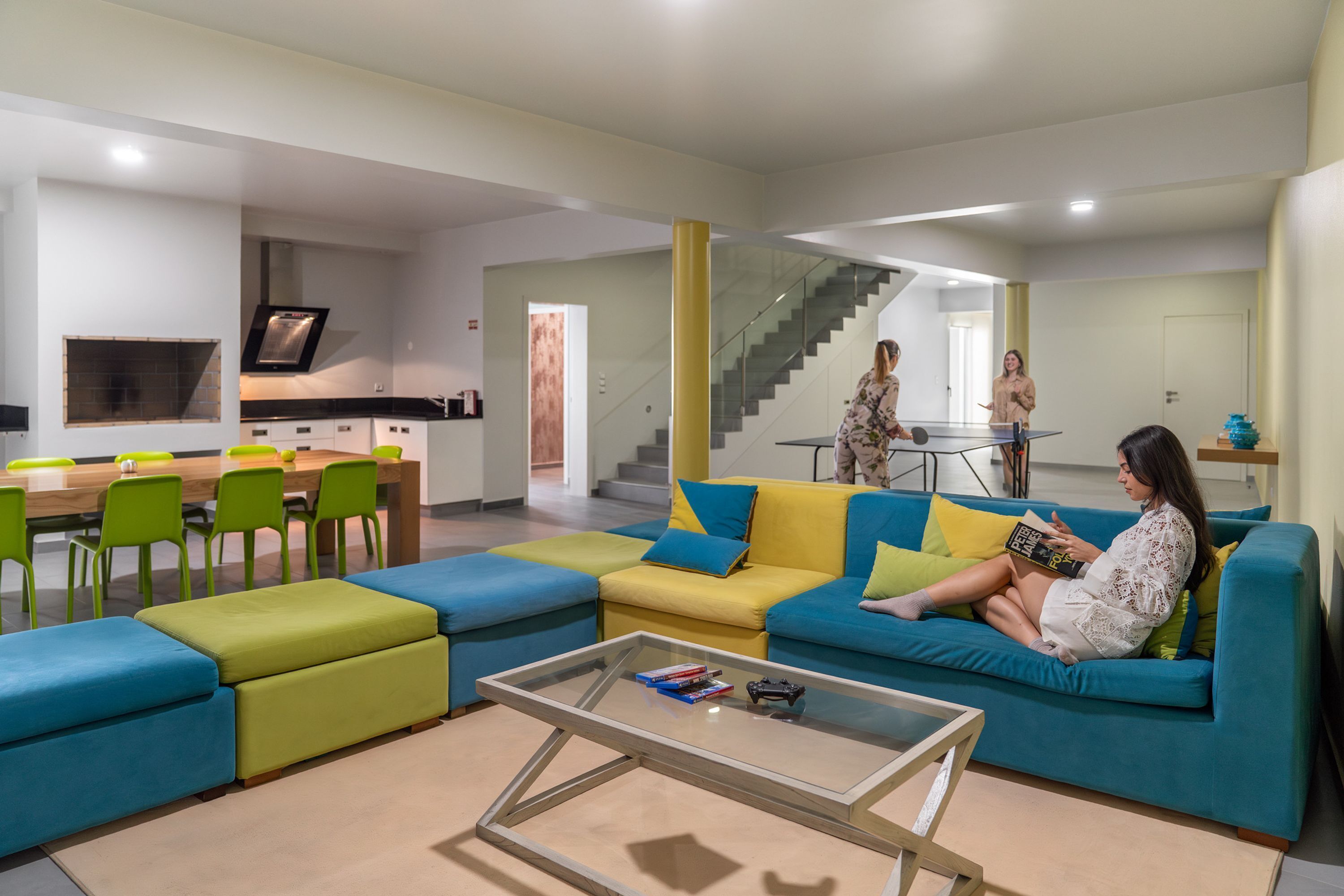 A modern living room with a sofa, coffee table, and a dining area with chairs and a table.