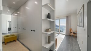 Une chambre d’hôtel moderne dotée d’une grande fenêtre, d’un canapé, d’un bureau et d’une étagère.