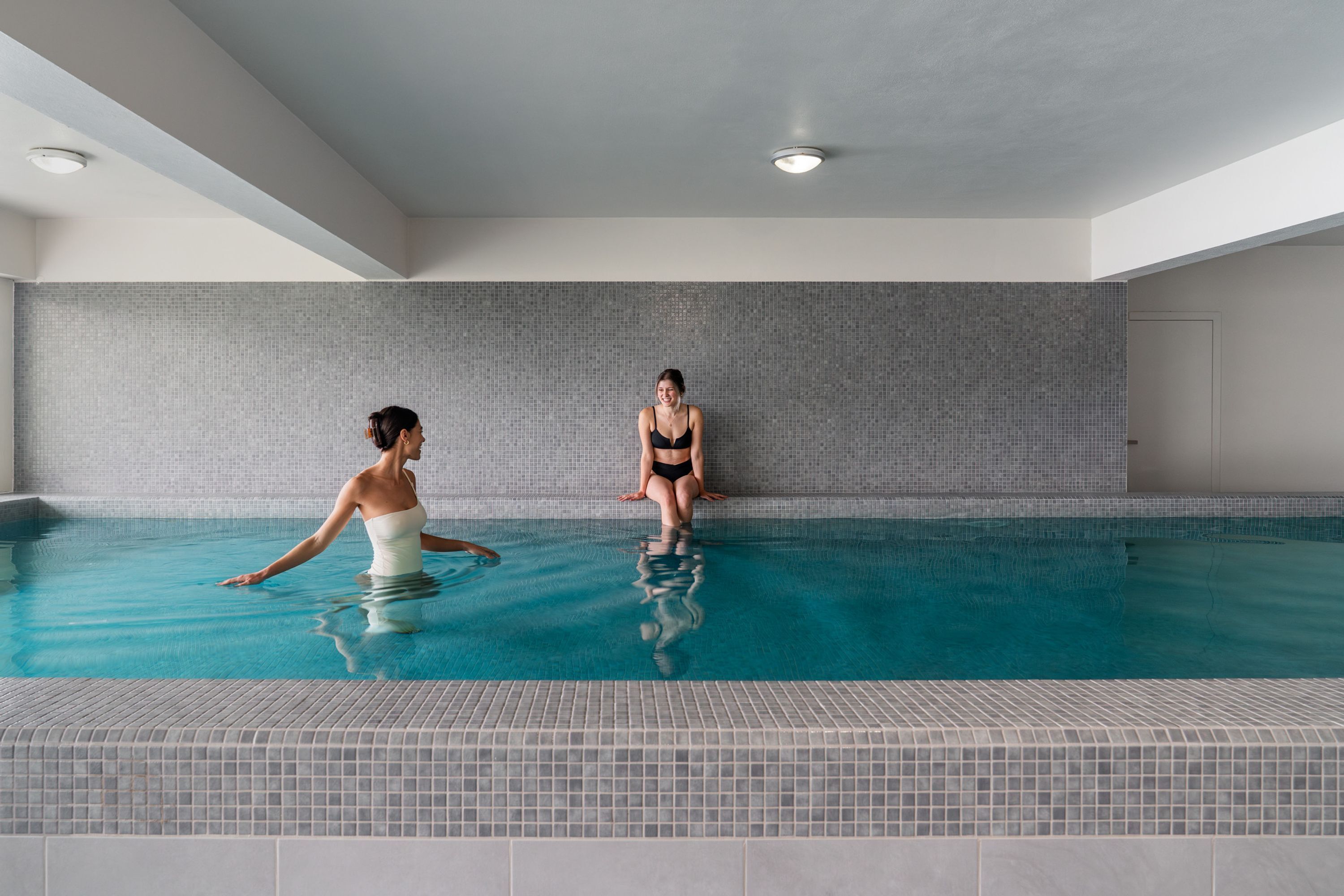 An indoor swimming pool with tiled walls and a tiled floor.
