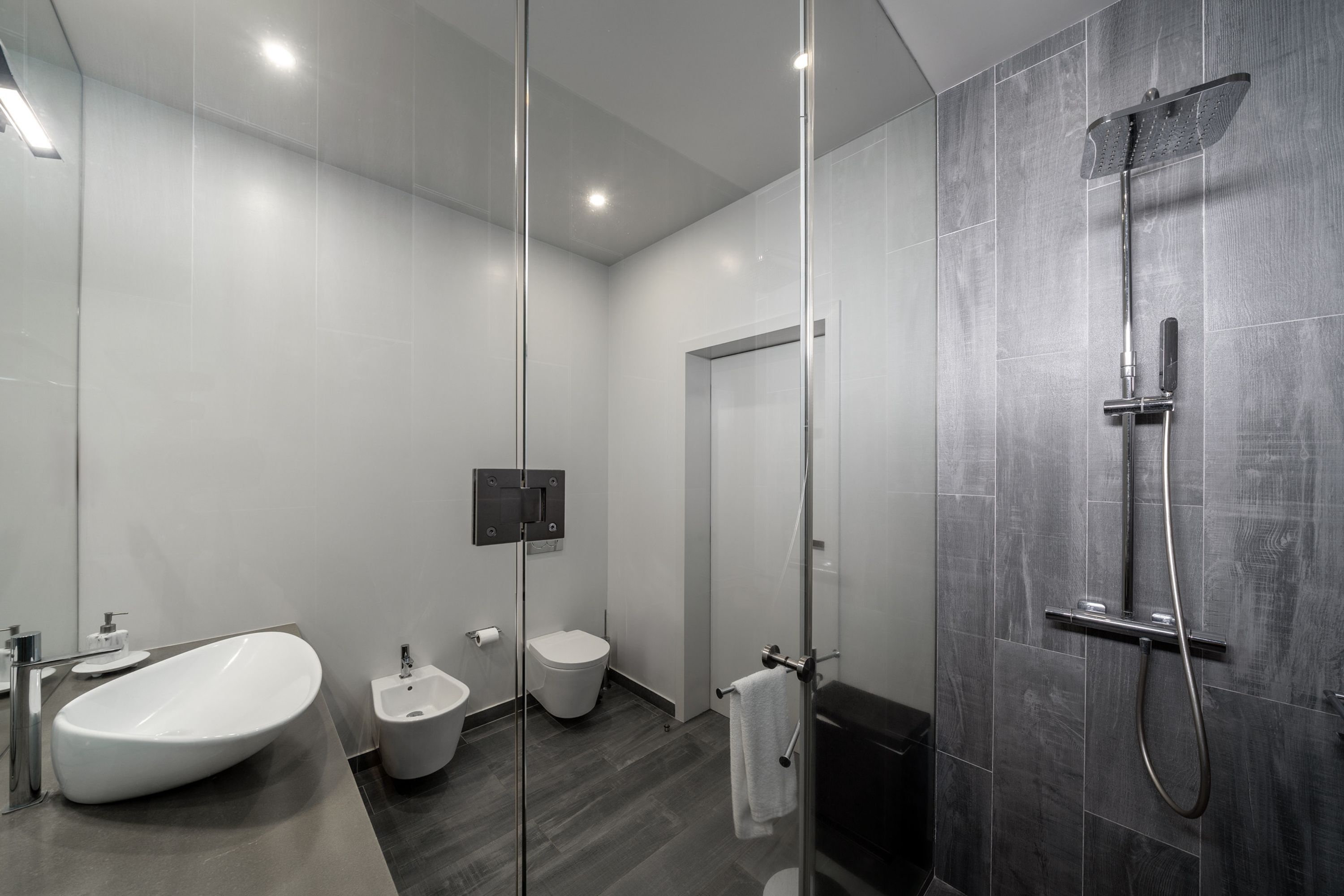 Un baño moderno con ducha acristalada, bañera independiente, bidé e inodoro.