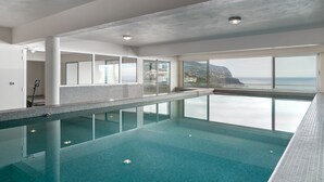 Une piscine intérieure offrant une vue dégagée sur l’océan et un espace balcon.