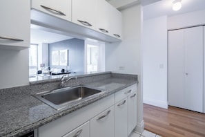 A modern kitchen with white cabinets, a granite countertop, and a stainless steel sink.