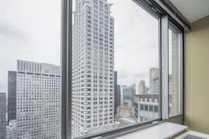 A room with a large window offering a view of tall buildings in a cityscape.