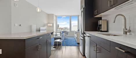 Una cocina moderna con gabinetes oscuros, un lavamanos de acero inoxidable y vistas al exterior.