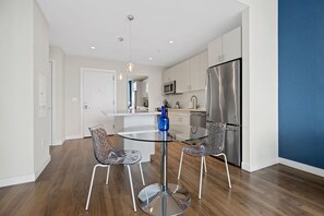 Una cucina moderna con un tavolo da pranzo in vetro, elettrodomestici in acciaio inossidabile e un vaso blu.
