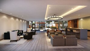 En rummelig lobby med receptionsdisk, siddeområde og en stor lysekrone.