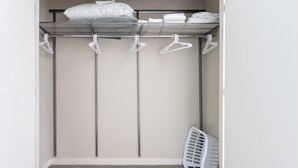 A walk-in closet with metal shelving, white hangers, and a white laundry basket. - Spacious One Bedroom in Luxury Boston Building (Boston)
