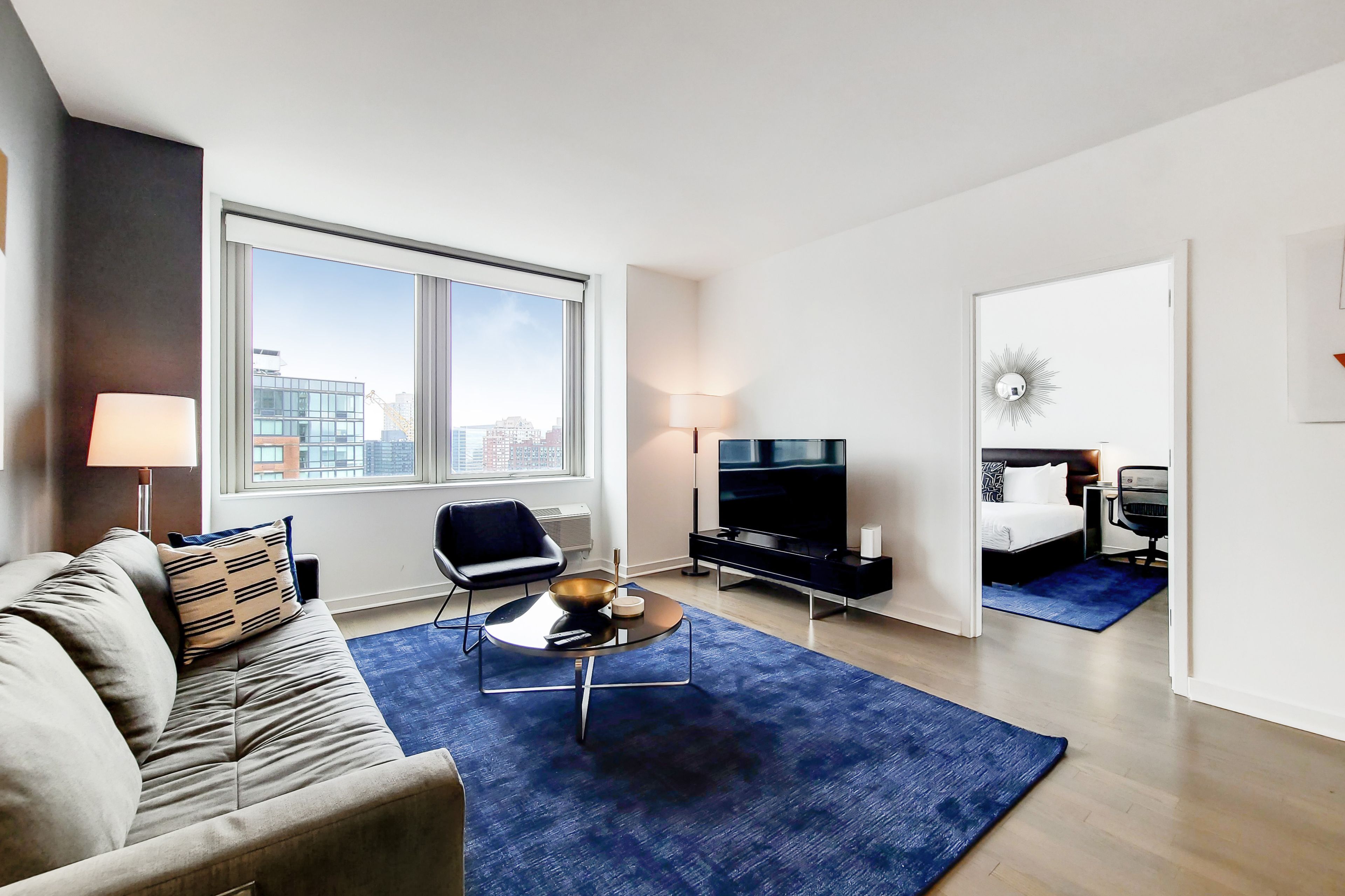 Een moderne hotelkamer met een bank, een salontafel, een televisie, een stoel en een bed.