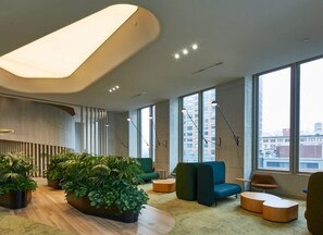Ein modernes Interieur mit gewölbter Decke, großen Fenstern, Sitzbereichen und Zimmerpflanzen.