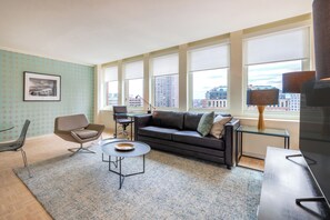 Relax in a stylish living space with a dark leather sofa, round coffee table, and city views.