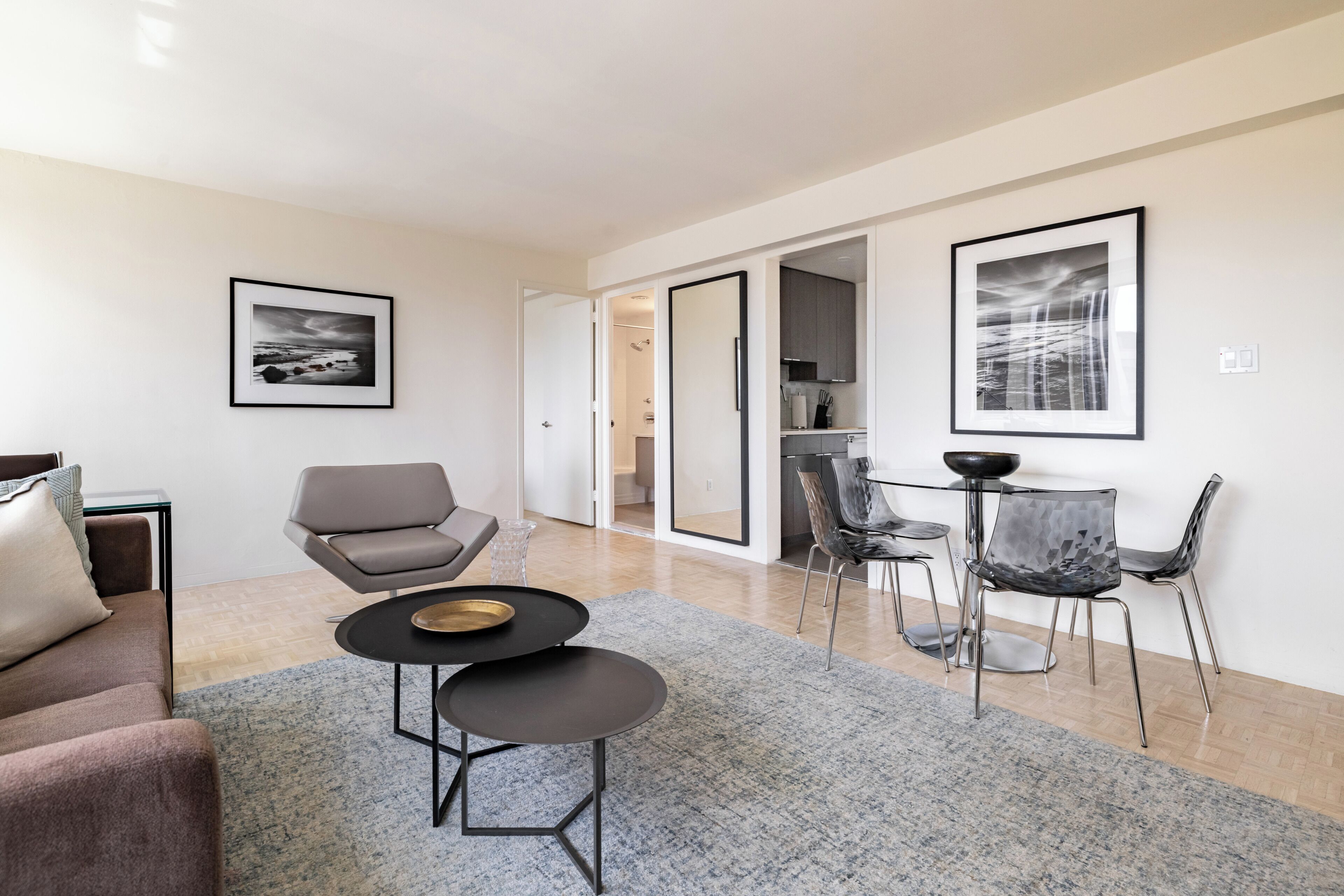 Un salon moderne comprenant un canapé, un fauteuil, une petite table et un coin repas avec des chaises et une table.