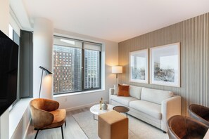 Een moderne woonkamer met een bank, fauteuils, een salontafel en een televisie.