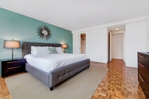 Une chambre à coucher comprenant un lit, des tables de chevet, un miroir et une armoire.