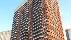 Un immeuble de grande hauteur doté d’une série de balcons disposés en réseau, d’un toit plat et d’un ciel dégagé en arrière-plan.