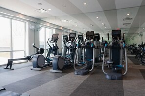 Une salle de sport équipée de divers appareils d’exercice, dotée de grandes fenêtres et présentant un design moderne et épuré.