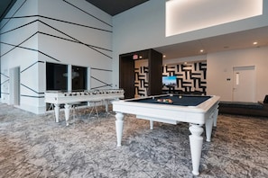 A billiards room with a pool table, foosball table, and a seating area with a patterned wall. - Stylish One Bedroom in White Plains - Near transit (White Plains)