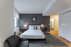 Une chambre à coucher moderne avec un grand lit, un miroir fixé au mur et une table de chevet avec une lampe.