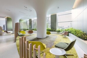 Un intérieur moderne avec un espace salon, de grandes fenêtres et des plantes d’intérieur.
