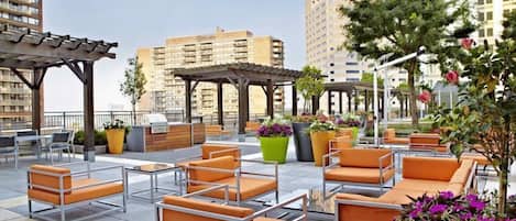 An outdoor seating area with multiple tables and chairs, surrounded by planters with flowers.