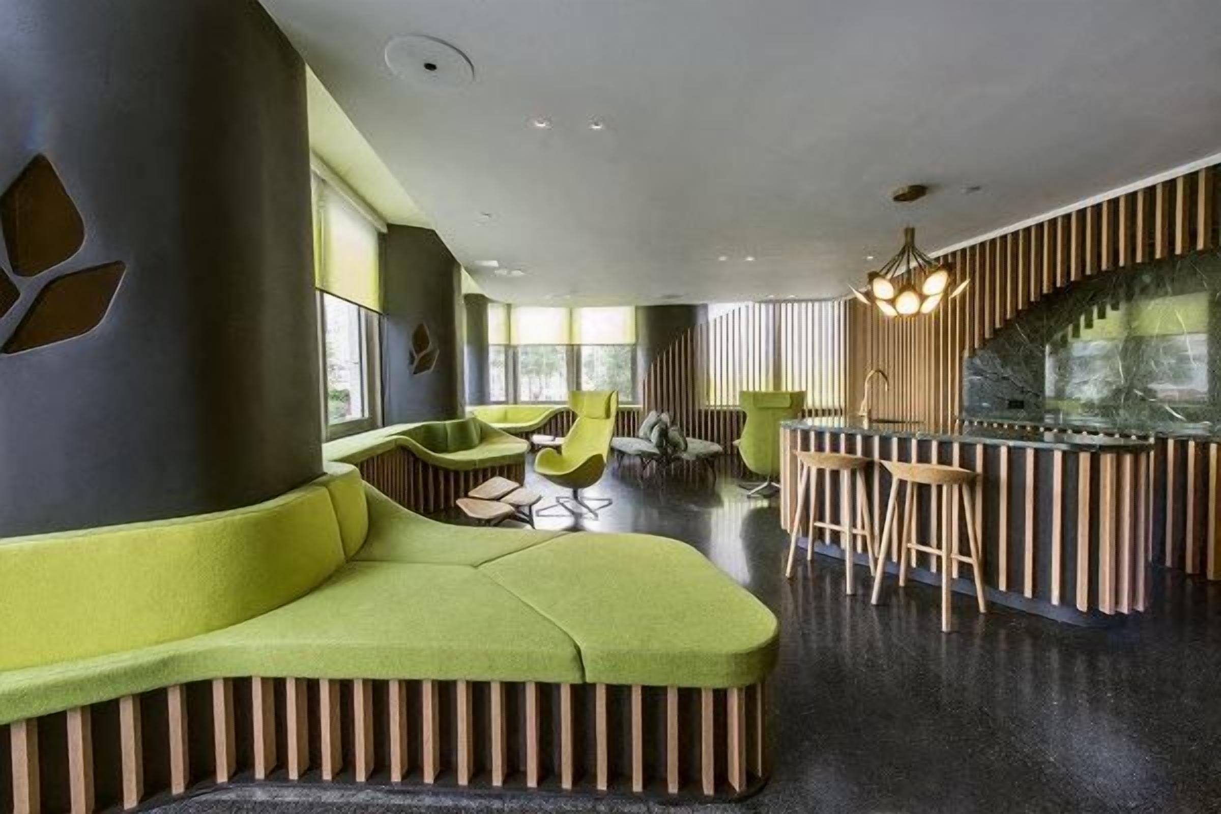 A modern interior with a curved seating area, a bar with stools, and a large window providing natural light.