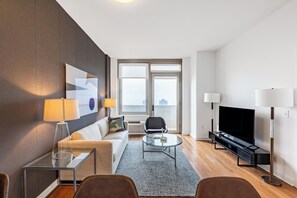 Un salon moderne avec un canapé, une table basse, un téléviseur et une lampe sur pied.