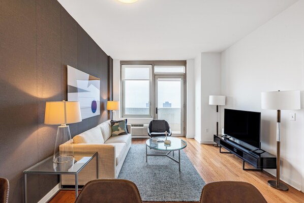 Ein modernes Wohnzimmer mit Sofa, Couchtisch, Fernseher und Stehlampe.