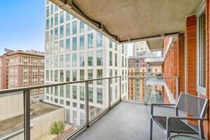 A balcony with a metal railing, a glass door, and a view of adjacent buildings. - Stylish One Bedroom Apartment in Back Bay (Boston)