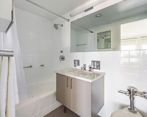 A modern bathroom with a bathtub, a sink, a mirror, and a shower. - Stylish One Bedroom Apartment in Back Bay (Boston)