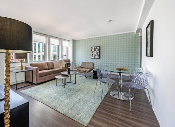A modern living room with a sofa, coffee table, and glass dining table.