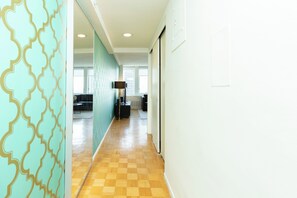 A hallway with patterned walls, a checkered floor, and a view into a living area with a sofa and a lamp. - One Bedroom Apartment in Back Bay Building (Boston)