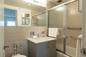 Ein modernes Badezimmer mit Duschkabine aus Glas, einem Waschbecken mit Spiegel darüber und einer Toilette.