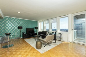 A modern living room with a sofa, TV, and glass dining table. - One Bedroom Apartment in Back Bay Building (Boston)