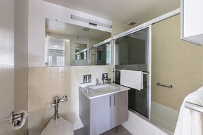 A bathroom with a sink, mirror, and shower. - One Bedroom Apartment W/ Luxury Amenities (Boston)