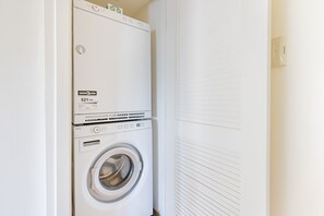 Uma máquina de lavar e secar empilhadas em um ambiente com paredes brancas e uma porta fechada.